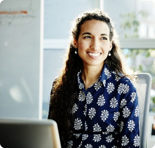 A woman smiling while sitting in front of her computer.