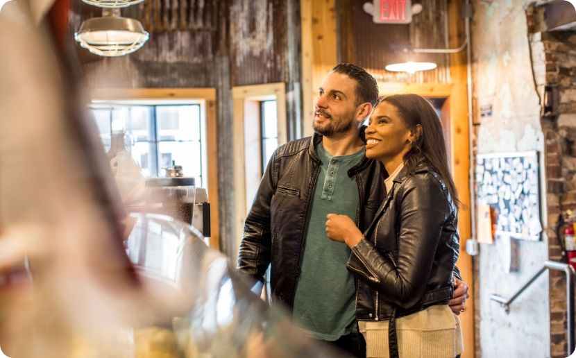 A couple mulling over the menu at a bar. 