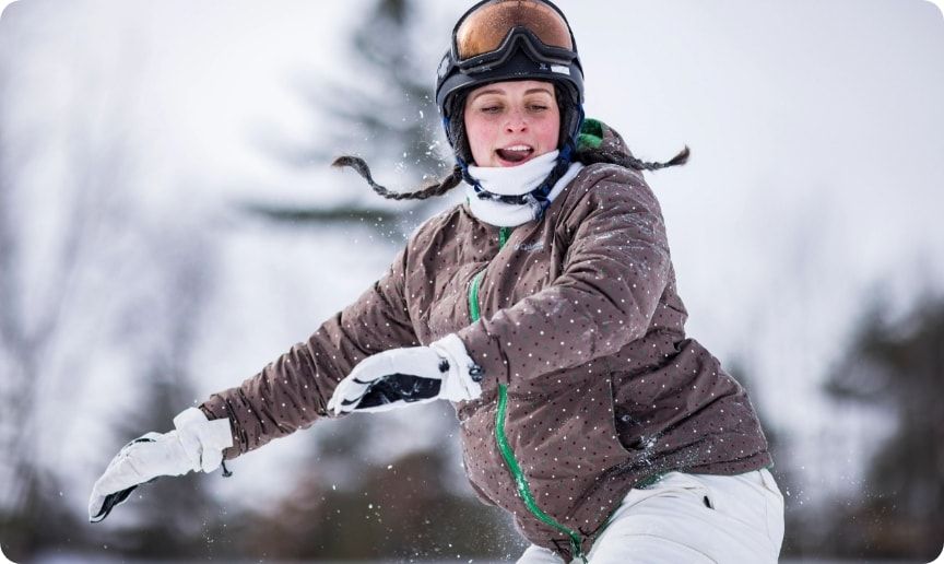 A woman snowboarding down a hill. 