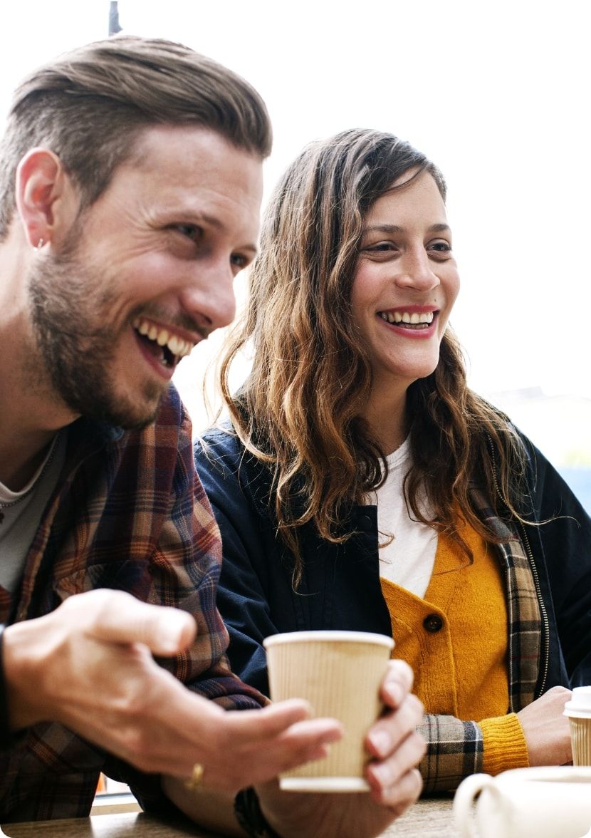 Two friends laugh while getting coffee. 