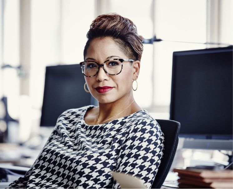 A woman sits in front of computers. 