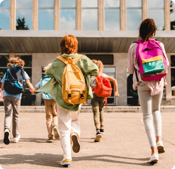 A group of kids with backpacks walk into a school building. 