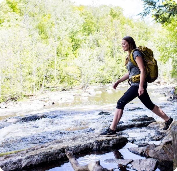 A hiker crosses a river. 