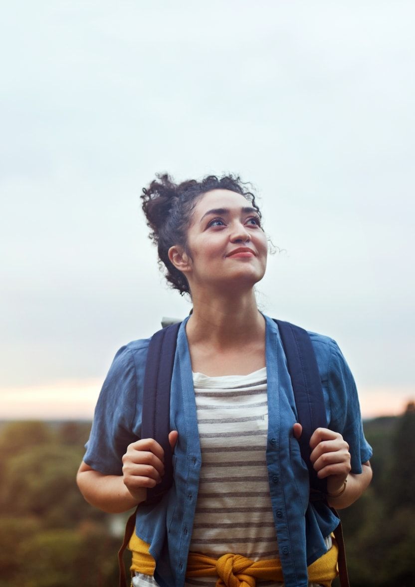 A woman at the top of a hill after walking up it on a cloudy day. 