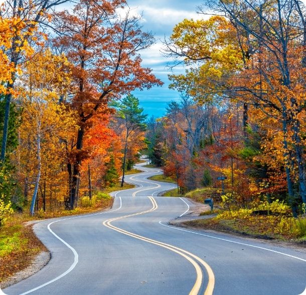 A scenic, curvy road, featuring vibrant fall foliage on either side. 