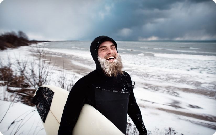 A surfer strolls along a snowy beach of Lake Michigan. 